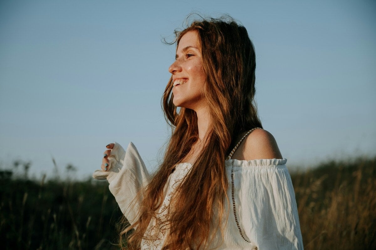 Een vrouw die buiten van een van de voordelen van breathwork geniet - minder stress.