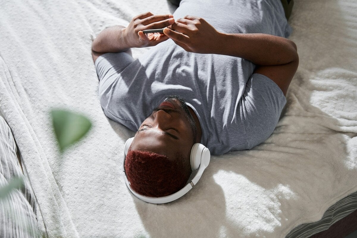 Man die op bed een begeleide audio over mediteren voor beginners luistert